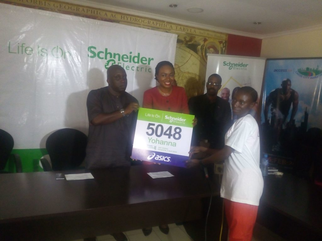 Chairman of the Lagos State Sports Commission Deji Tinubu (L) and Anne Eze (C) hand Yohanna her bib number.