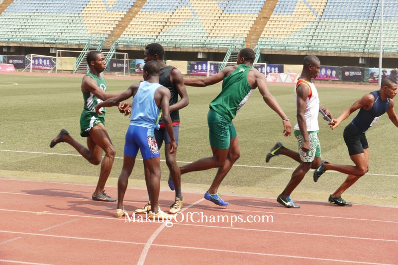 Oguma reaching out to Jakpa and handing him the baton in the 4x200m relay